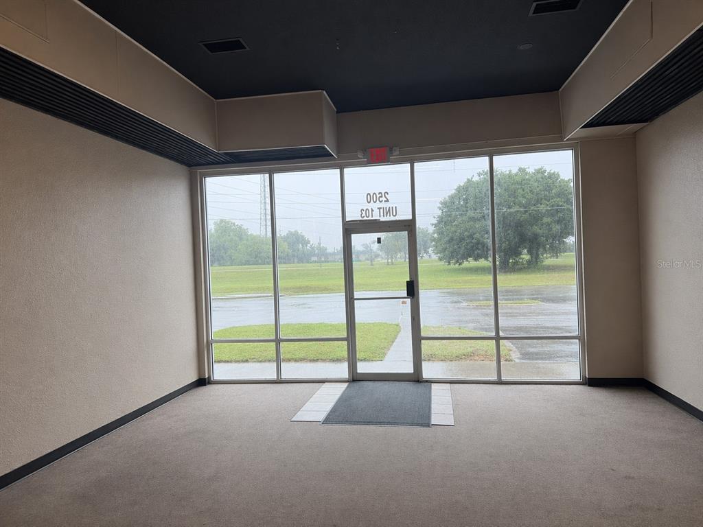 An empty commercial office space features beige walls, a black ceiling, and large glass windows — 2500 NW 6TH STREET UNIT 103, OCALA, FL