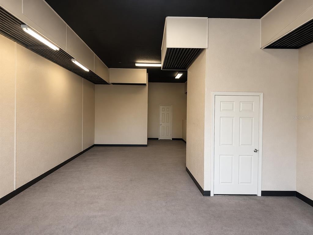 An interior room features gray carpeting, beige walls, a black ceiling, and two white doors — 2500 NW 6TH STREET UNIT 103, OCALA, FL
