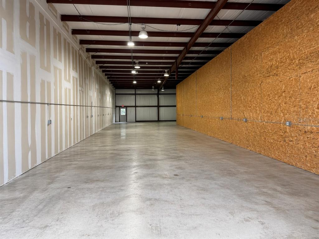 An empty industrial warehouse space features a concrete floor, exposed ceiling beams, and contrasting walls — 2500 NW 6TH STREET UNIT 103, OCALA, FL