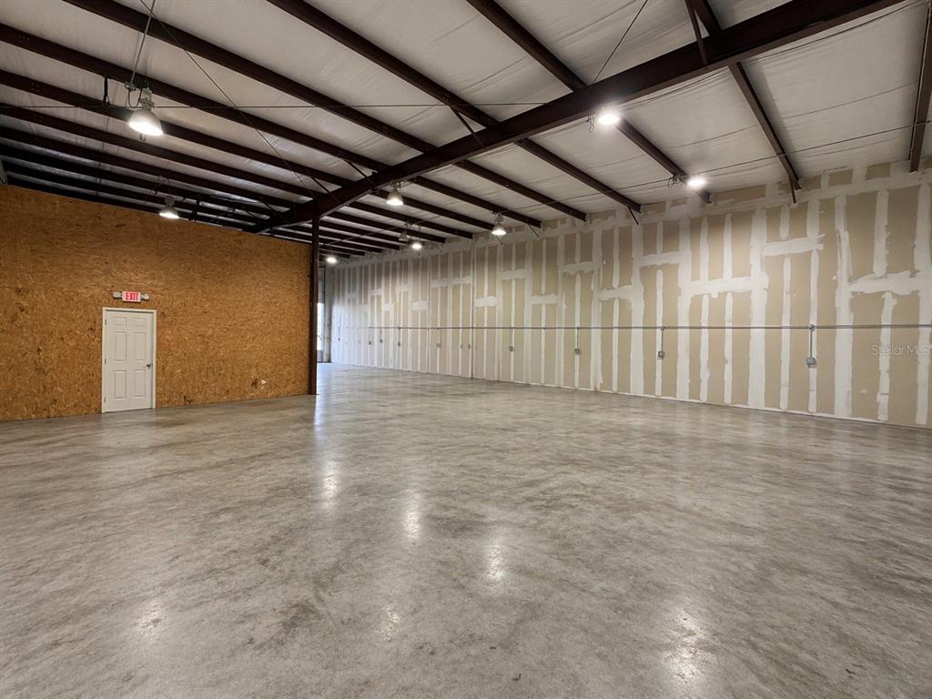 An empty warehouse space features a concrete floor, exposed steel beams, and unfinished drywall walls — 2500 NW 6TH STREET UNIT 103, OCALA, FL