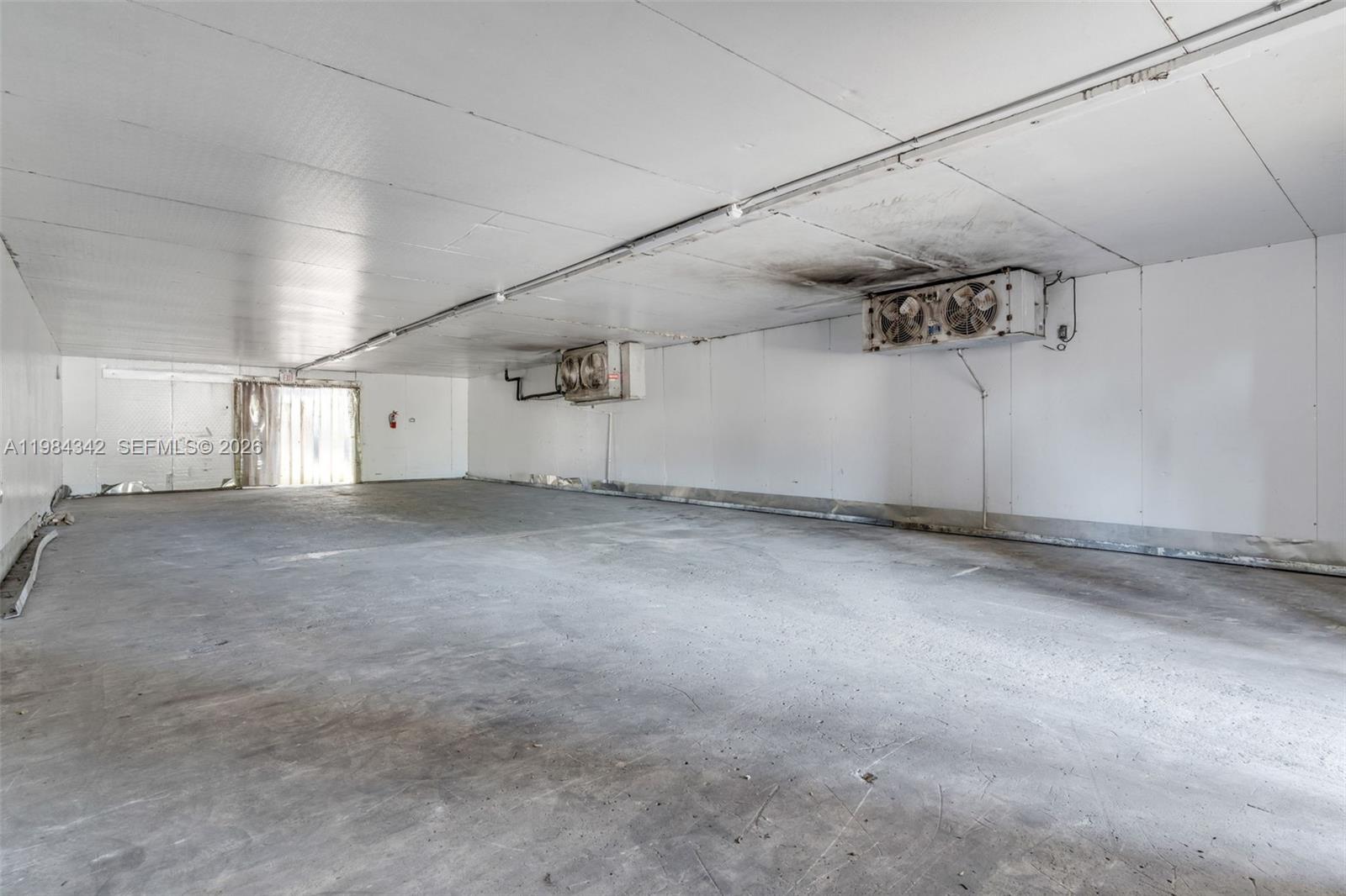 This is a large, empty walk-in cooler with concrete floors and ceiling-mounted refrigeration units — 20601 SW 194th Ave, Miami FL 33187, MIAMI, FL