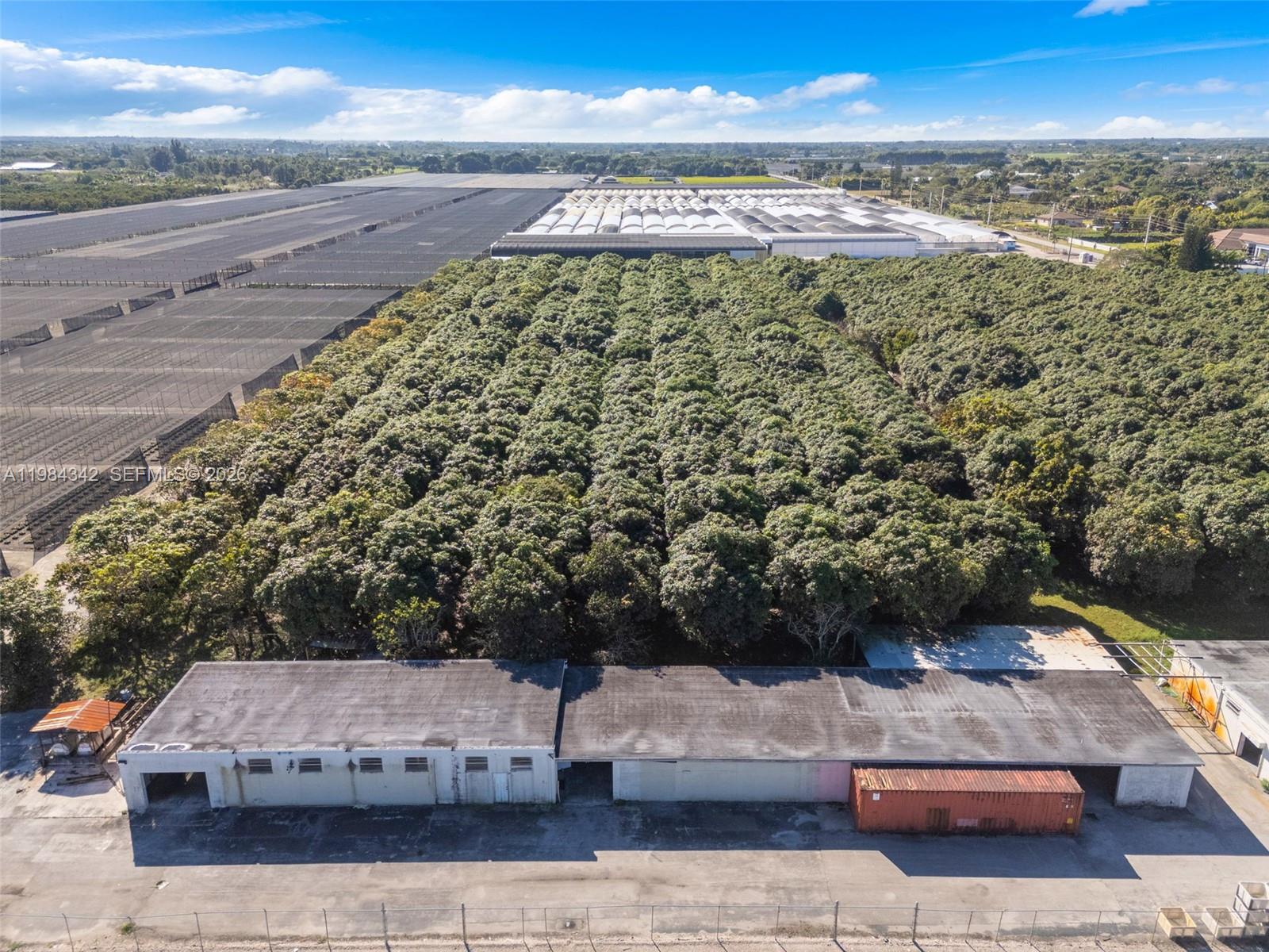 An aerial view shows a long warehouse building in front of a large orchard — 20601 SW 194th Ave, Miami FL 33187, MIAMI, FL