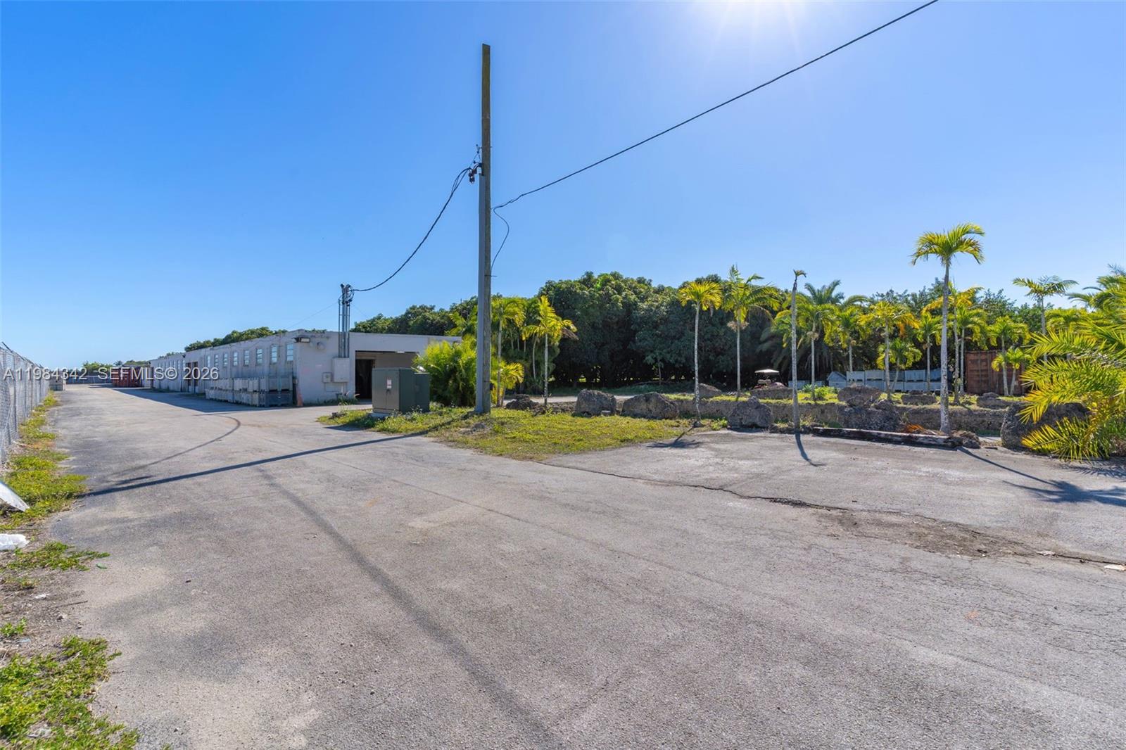 An outdoor view shows a paved lot, a utility pole, and a long industrial building — 20601 SW 194th Ave, Miami FL 33187, MIAMI, FL