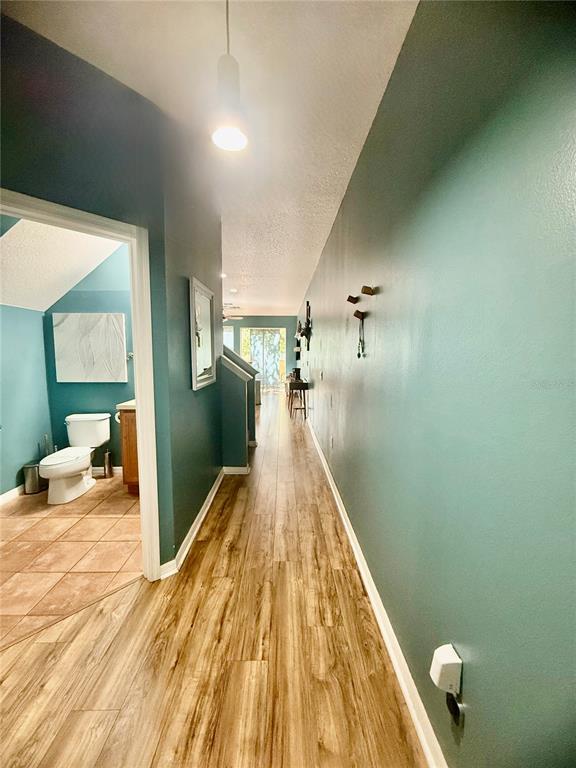 A hallway features teal walls, wood-look flooring, and a white brick-patterned staircase wall — 2672 MAYAGUANA STREET, KISSIMMEE, FL