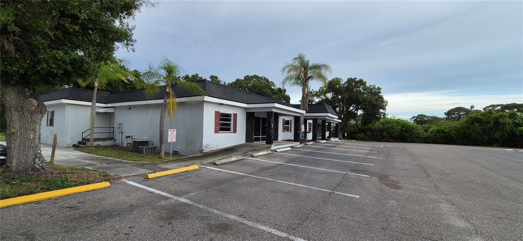 A single-story commercial building with a parking lot and palm trees under a cloudy sky — 7789 131ST STREET N, SEMINOLE, FL