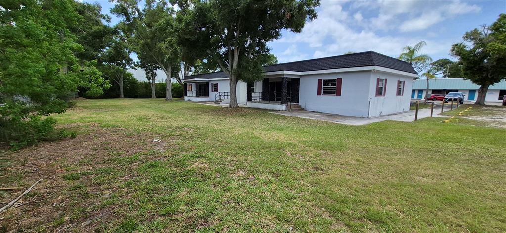 A single-story white building with a dark roof sits on a large grassy lot — 7789 131ST STREET N, SEMINOLE, FL