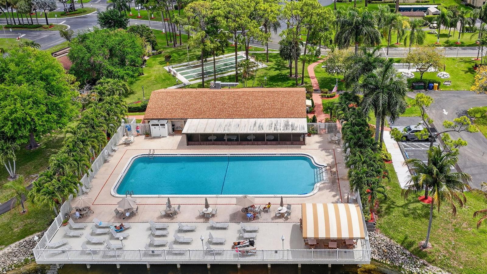 An aerial view shows a rectangular swimming pool with a deck, lounge chairs, and building — 624 Sea Pine Way # B3, FL 33415, FL