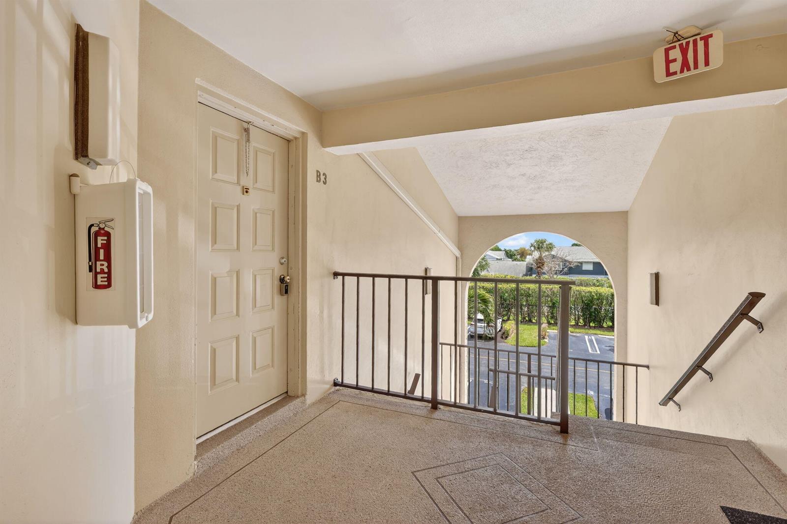 An outdoor apartment landing features a beige door labeled B3, a fire extinguisher, and stairs — 624 Sea Pine Way # B3, FL 33415, FL