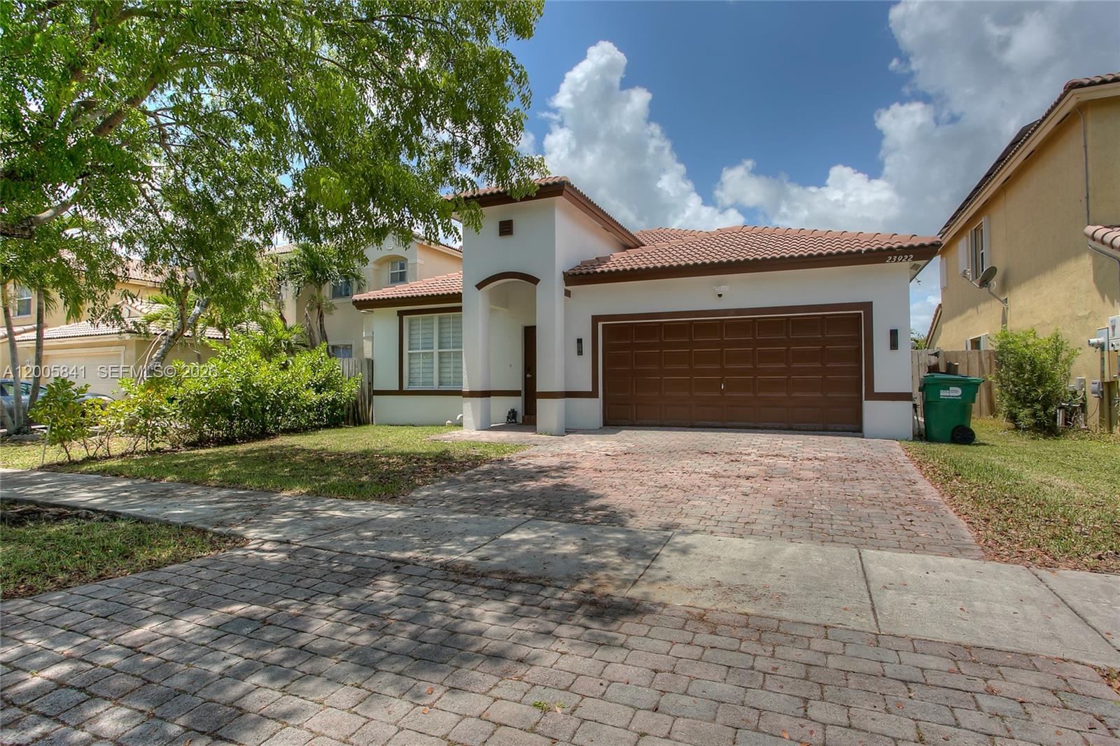 A single-story house with a white stucco exterior, brown garage door, and tiled roof — 23922 SW 108th Ave, Homestead FL 33032, HOMESTEAD, FL