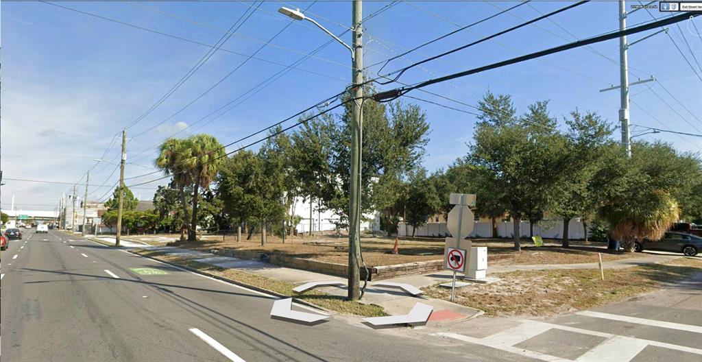 A vacant corner lot with trees and a utility pole sits beside a paved road — 1101 N HOWARD AVENUE, TAMPA, FL