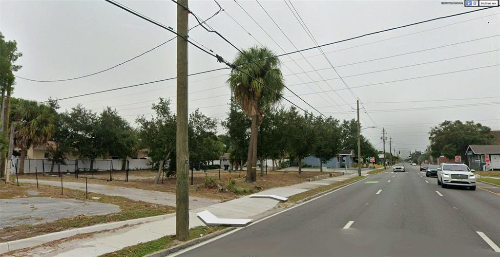 A vacant, grassy lot sits along a paved road with a sidewalk and utility poles — 1101 N HOWARD AVENUE, TAMPA, FL