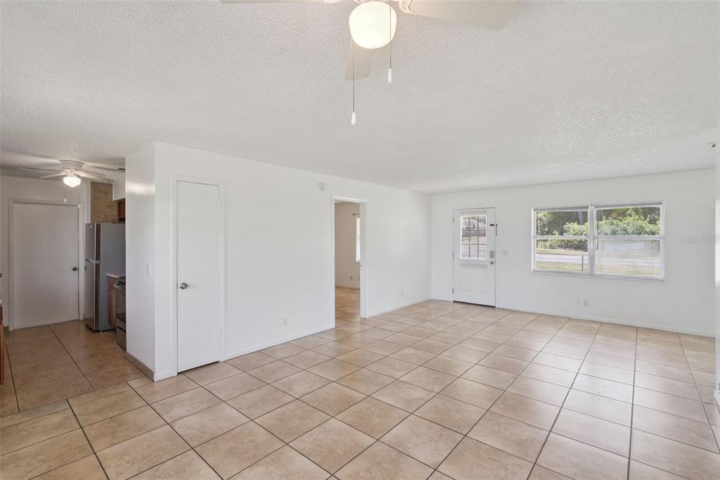 An open living area features white walls, tan tile flooring, and a ceiling fan — 4225 NE 25TH AVENUE, OCALA, FL