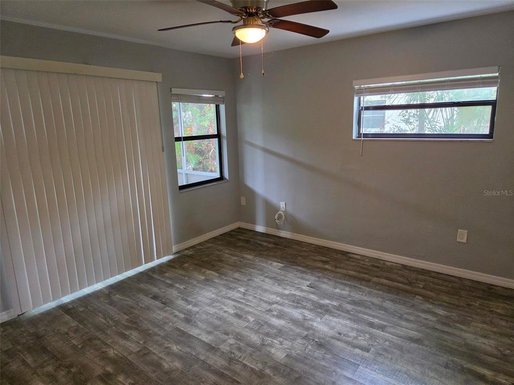 A bedroom with gray walls, wood-look flooring, a ceiling fan, and two windows — 2939 LOS ALTOS DRIVE UNIT B, BELLEAIR BLUFFS, FL
