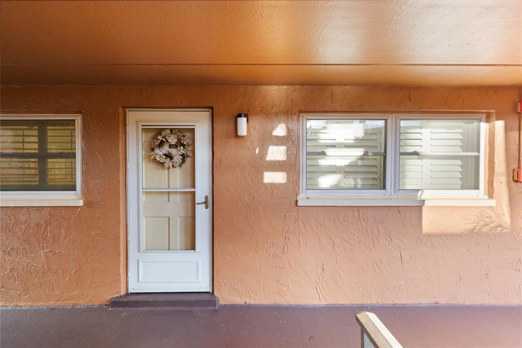 The exterior view shows a peach-colored wall with a white door and two windows — 12760 INDIAN ROCKS ROAD UNIT 516, LARGO, FL