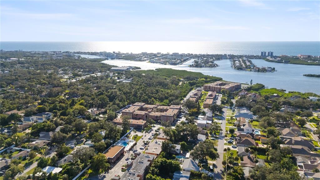An aerial view shows a residential neighborhood with apartment complexes near a coastal waterway — 12760 INDIAN ROCKS ROAD UNIT 516, LARGO, FL