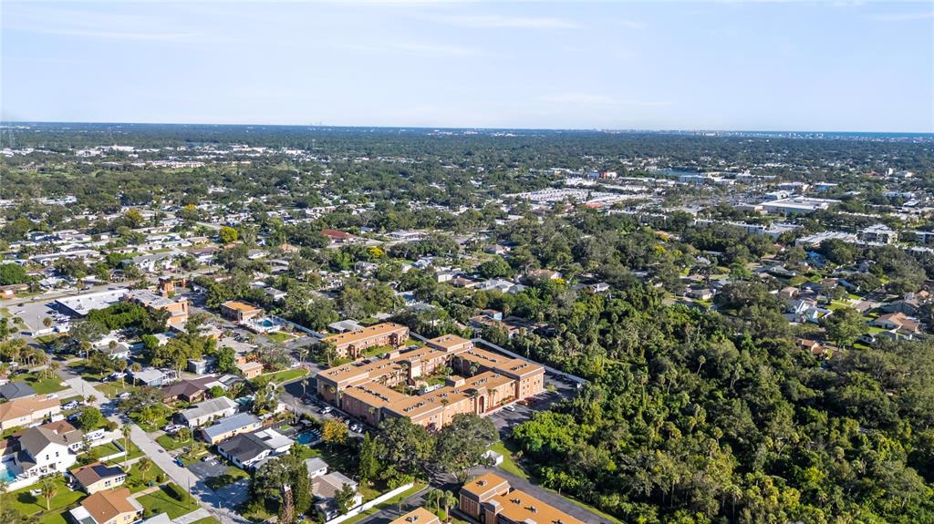 An aerial view shows a multi-story apartment complex surrounded by trees and suburban residential neighborhoods — 12760 INDIAN ROCKS ROAD UNIT 516, LARGO, FL