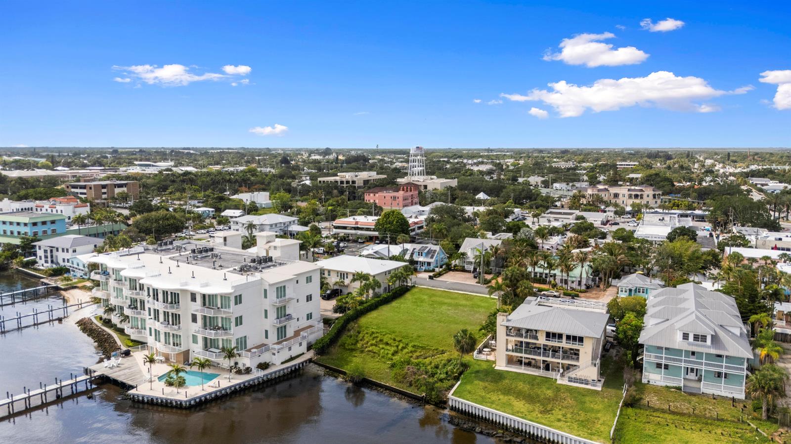 An aerial view shows waterfront residential buildings, a vacant grassy lot, and a distant water tower — 39 SE Seminole Street, Stuart FL 34994, STUART, FL