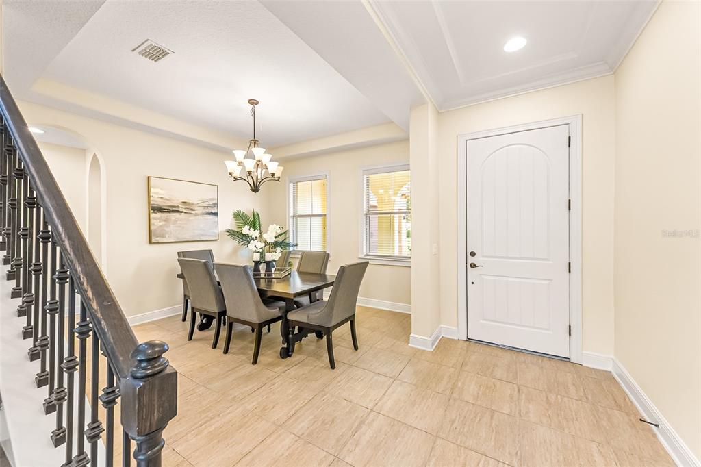 A dining area with a table and chairs sits near a staircase and front door — 14252 CREEKBED CIRCLE, WINTER GARDEN, FL