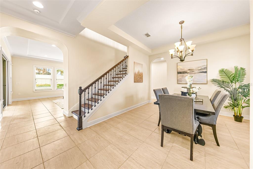 A dining area with a staircase, tile flooring, and a chandelier in an open-concept home — 14252 CREEKBED CIRCLE, WINTER GARDEN, FL
