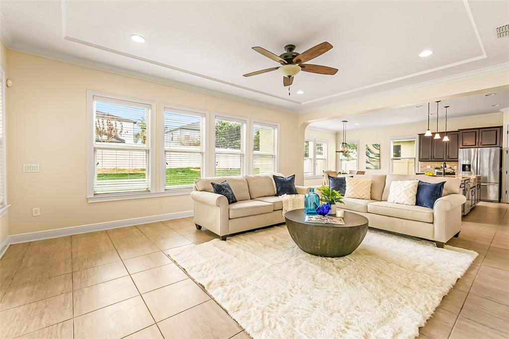 A living room with beige tile floors, a cream sofa, and a large circular coffee table — 14252 CREEKBED CIRCLE, WINTER GARDEN, FL