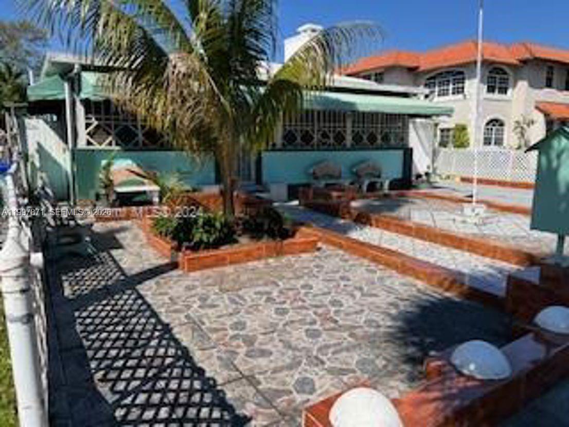 A paved patio area features a palm tree, brick planters, and a covered porch — 5934 NE 4th ct, Miami FL 33137, MIAMI, FL