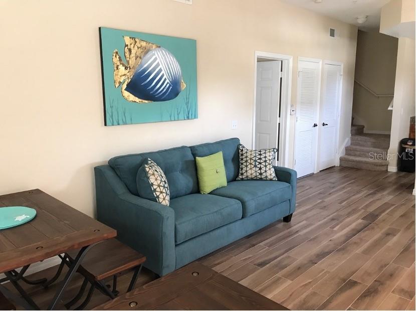 A living room features a teal sofa, a wooden table, and a fish painting — 4010 SANTA MARIA DRIVE UNIT 101, KISSIMMEE, FL