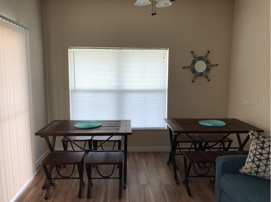 A dining area features two wooden tables with metal frames, stools, and a ship-wheel wall decoration — 4010 SANTA MARIA DRIVE UNIT 101, KISSIMMEE, FL