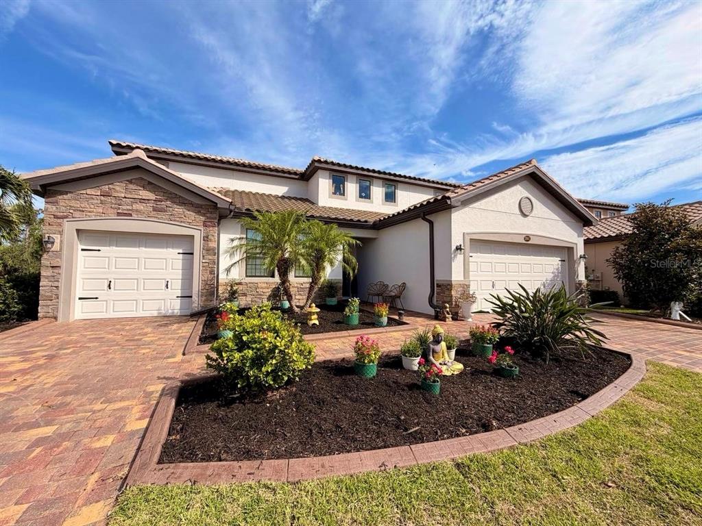 A two-story house with a stone facade, two garage doors, and a landscaped front yard — 20642 BENISSIMO DRIVE, VENICE, FL