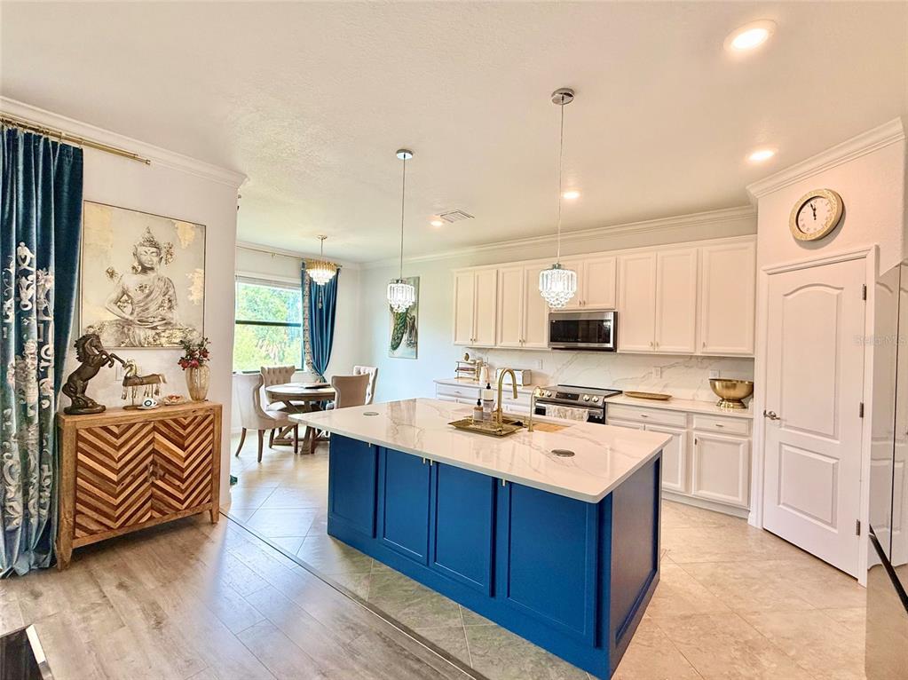 A kitchen features a blue island with a white countertop, white cabinets, and tile flooring — 20642 BENISSIMO DRIVE, VENICE, FL