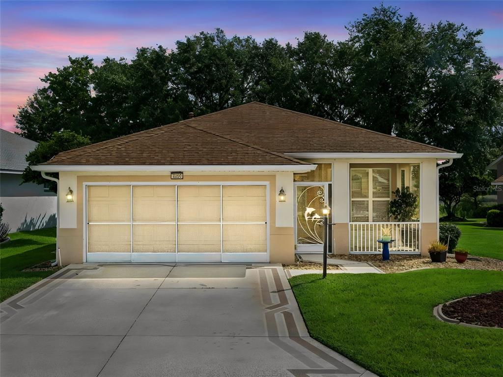A single-story house with a tan stucco exterior, a brown roof, and a two-car garage — 4519 INVERNESS DRIVE, LEESBURG, FL