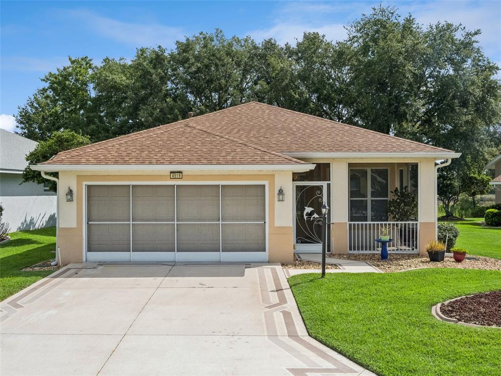 A single-story house with a tan stucco exterior, a brown shingled roof, and a screened garage — 4519 INVERNESS DRIVE, LEESBURG, FL