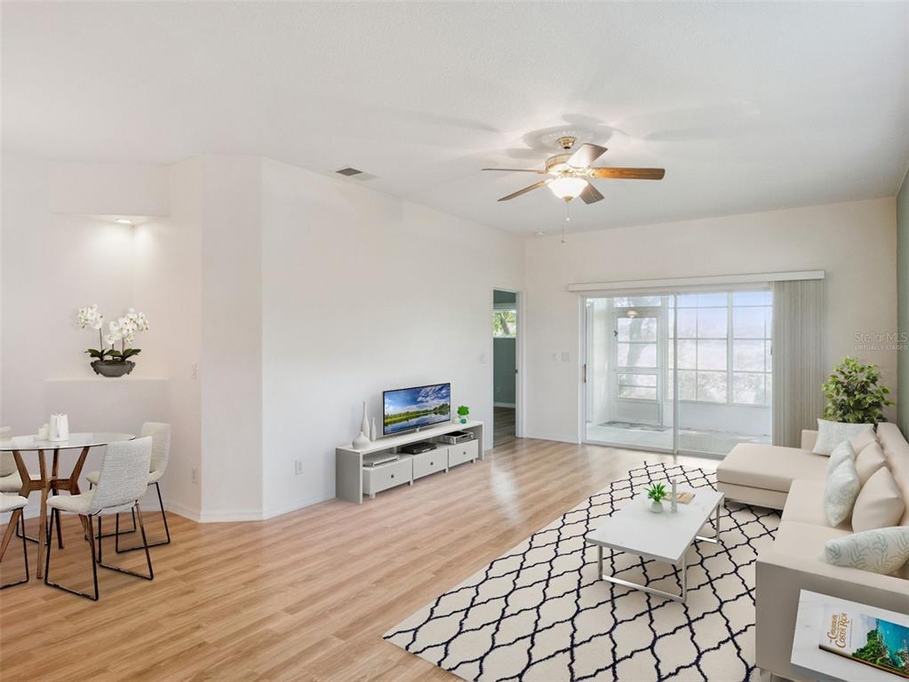 A living room with light wood floors, a ceiling fan, and a sliding glass door — 4519 INVERNESS DRIVE, LEESBURG, FL