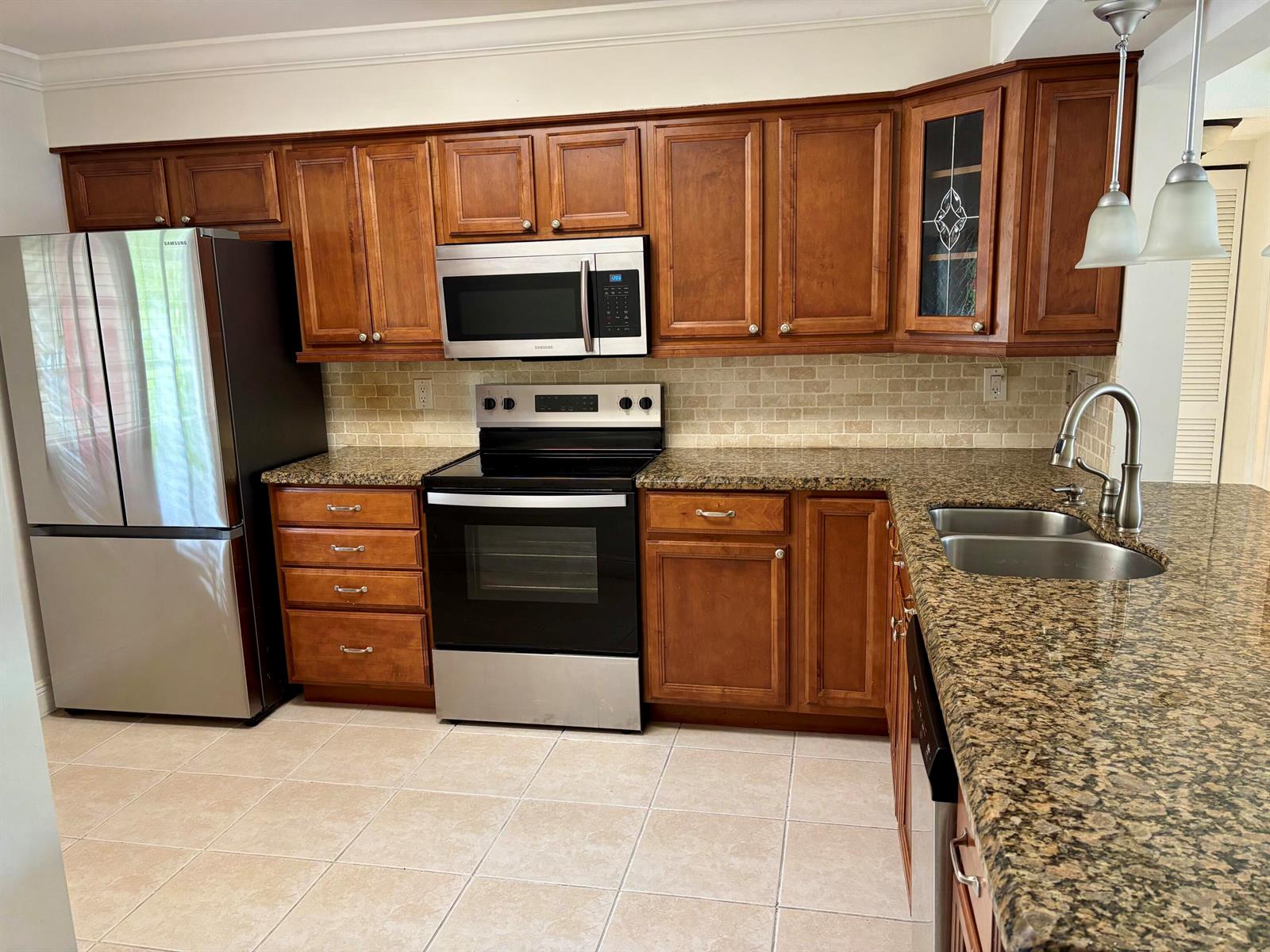 A kitchen featuring wood cabinets, granite countertops, stainless steel appliances, and a tiled backsplash — 4040 Crystal Lake Drive # 101, Pompano Beach FL 33064, POMPANO BEACH, FL