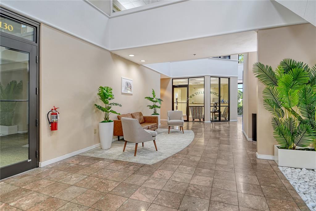 A bright office building lobby features tiled floors, a seating area, and potted plants — 3639 CORTEZ ROAD W UNIT 225, BRADENTON, FL