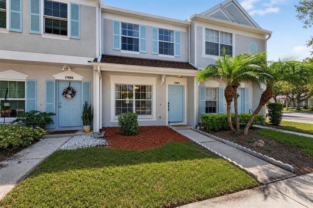 A two-story townhouse exterior features light gray siding, blue shutters, and two front doors — 17403 FLATWOODS KEY DRIVE, TAMPA, FL