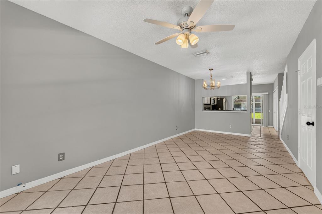 A living room with gray walls, tile flooring, a ceiling fan, and a pass-through window — 17403 FLATWOODS KEY DRIVE, TAMPA, FL