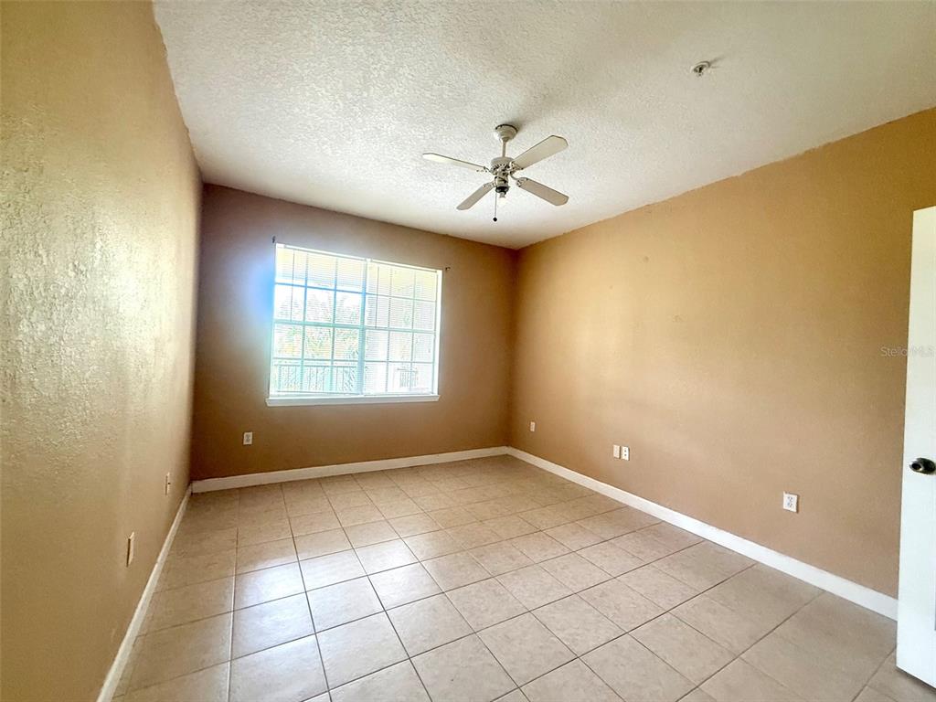 An empty bedroom with tan walls, a ceiling fan, and light-colored tile flooring — 2668 ROBERT TRENT JONES DRIVE UNIT 434, ORLANDO, FL