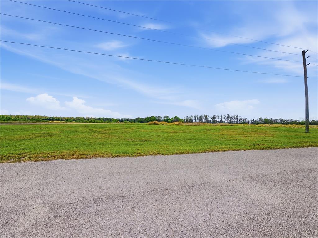 A wide, flat, grassy vacant lot is bordered by an asphalt road and utility pole — TBD TIMBERS DRIVE, FORT MEADE, FL