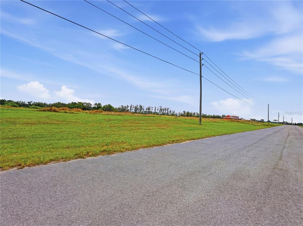 A paved road runs alongside a large, grassy, undeveloped lot under a blue sky — TBD TIMBERS DRIVE, FORT MEADE, FL