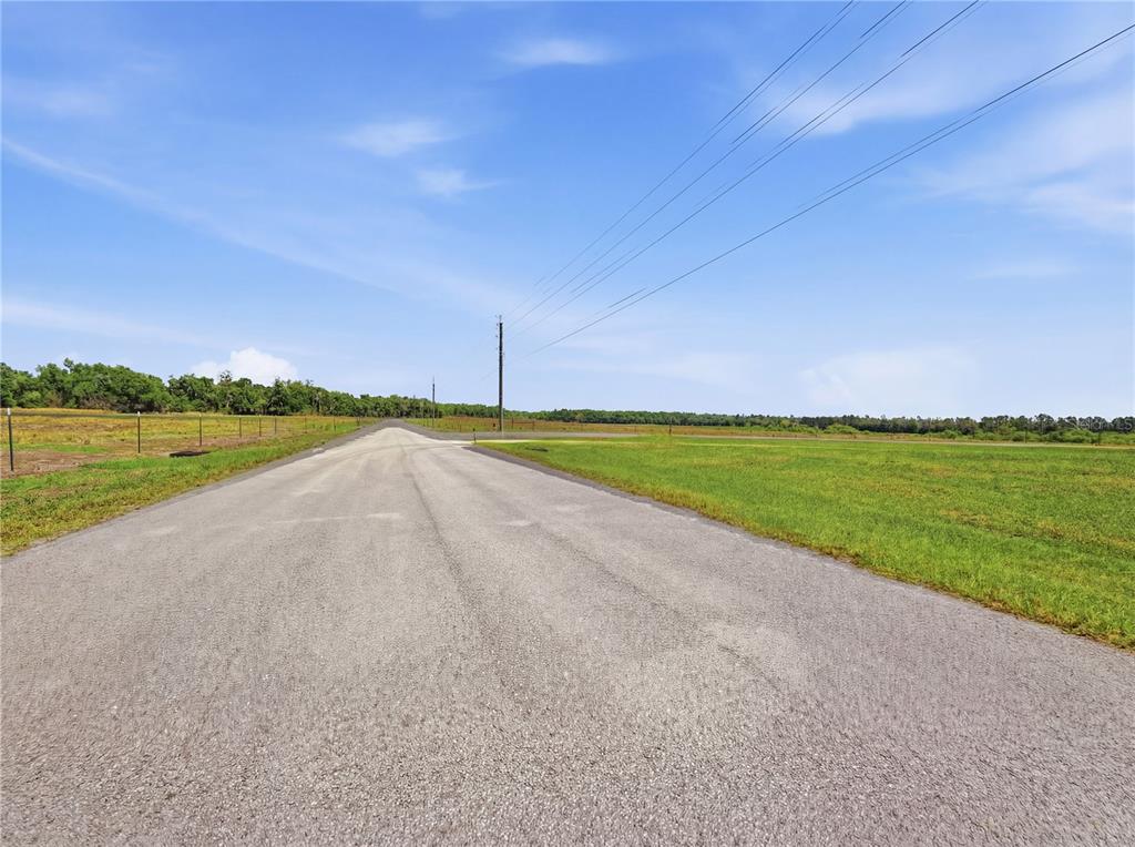 A paved road stretches through an open, grassy field under a clear blue sky — TBD TIMBERS DRIVE, FORT MEADE, FL