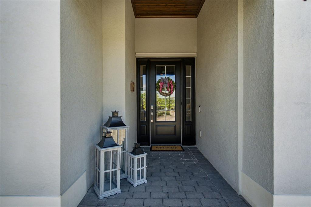 A front entryway features a black door with a wreath, stone flooring, and decorative lanterns — 15967 TALON TERRACE, PUNTA GORDA, FL