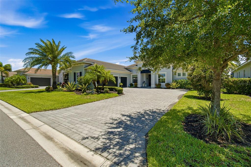 A light blue single-story house with a paved driveway, palm trees, and a manicured lawn — 15967 TALON TERRACE, PUNTA GORDA, FL