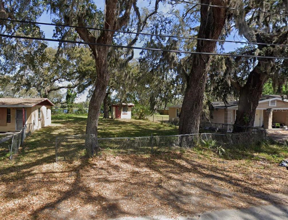 A grassy lot sits between two small houses with large trees and a chain-link fence — 529 FULTON STREET, DAYTONA BEACH, FL
