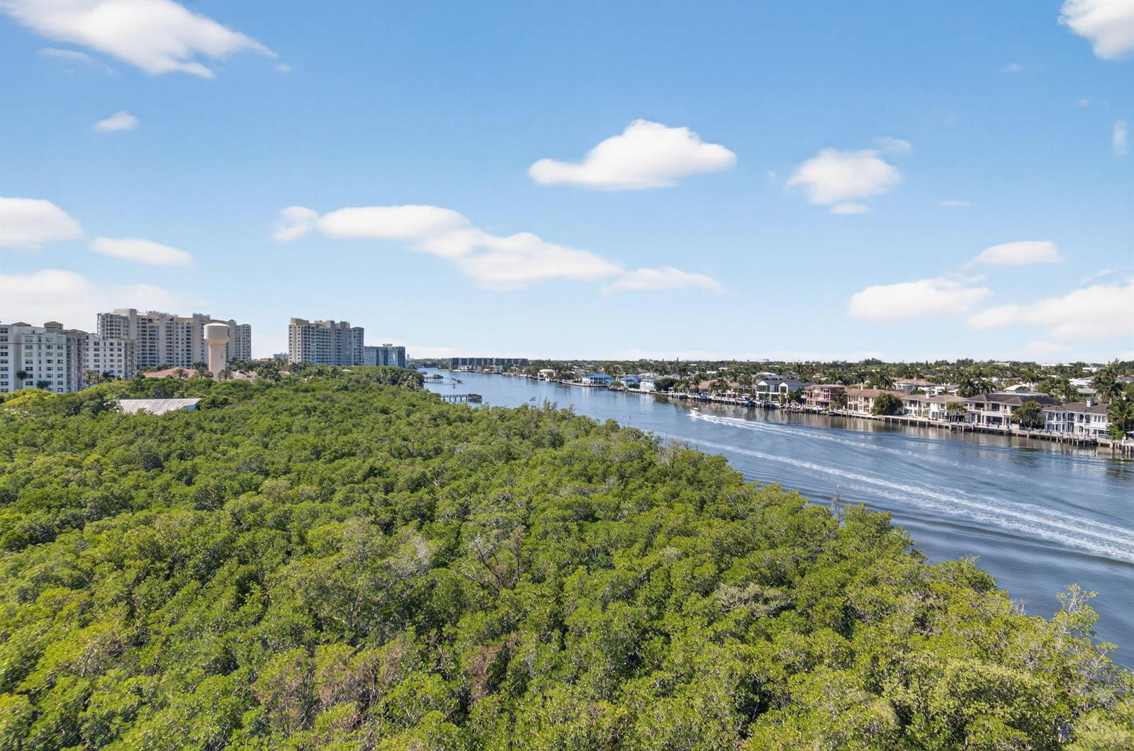 An aerial view shows a waterway lined with houses and a dense forest area — 3420 S Ocean Boulevard # 8z, Highland Beach FL 33487, HIGHLAND BEACH, FL
