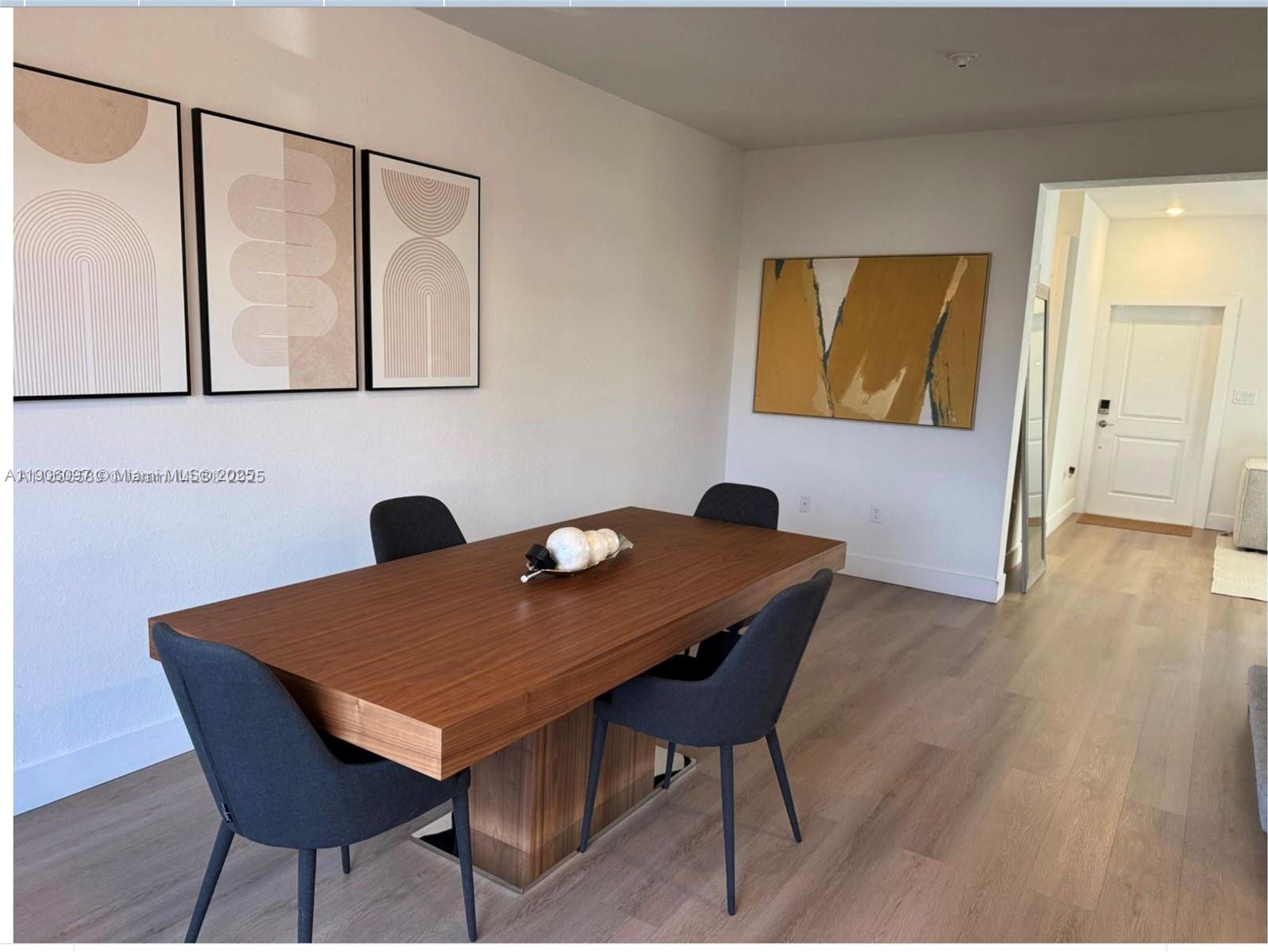 A dining room features a wooden table, four dark chairs, and abstract wall art — 12277 NW 24th Pl, Miami FL 33167, MIAMI, FL