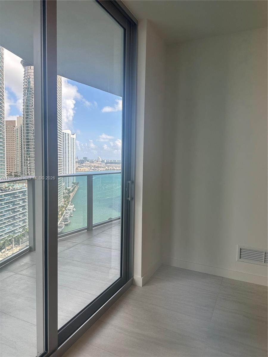 A room with light tile flooring and a sliding glass door opening to a balcony — 77 SE 5th st # 2506, Miami FL 33131, MIAMI, FL