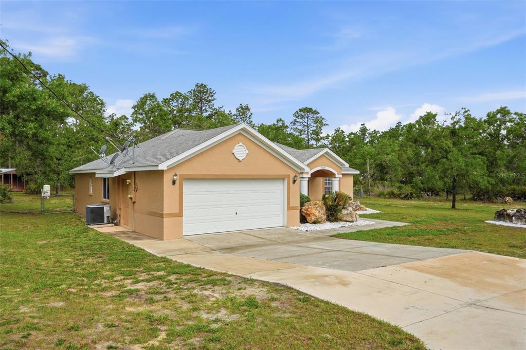 A tan single-story house with a two-car garage and a concrete driveway — 17469 MABERLY ROAD, WEEKI WACHEE, FL