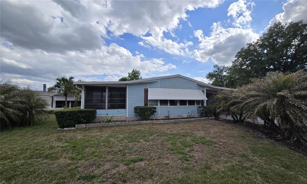 A light blue single-story manufactured home features a screened porch and a grassy front yard — 2691 LAKE GRASSMERE CIRCLE UNIT 904, ZELLWOOD, FL