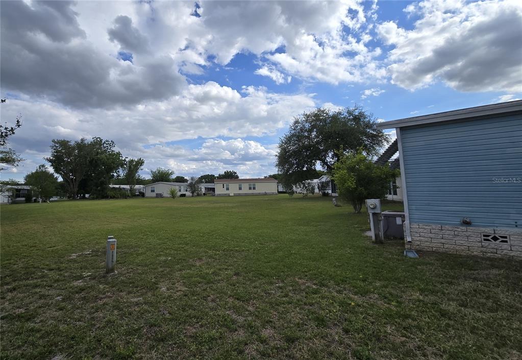 A grassy lot sits between mobile homes under a cloudy sky — 2691 LAKE GRASSMERE CIRCLE UNIT 904, ZELLWOOD, FL