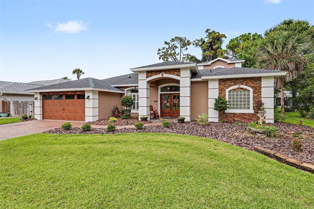 A single-story house with a brick driveway, two-car garage, and a stone-accented entryway — 663 SHERIDAN WOODS DR, MELBOURNE, FL